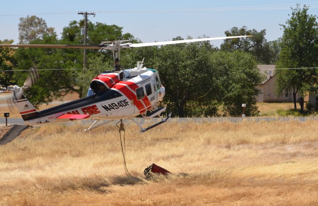 Cal Fire helicopter taking off after being refueled on the ground by a gas tanker. 